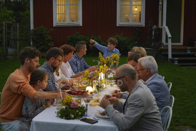 Family enjoying candlelight garden dinner party — Stock Photo