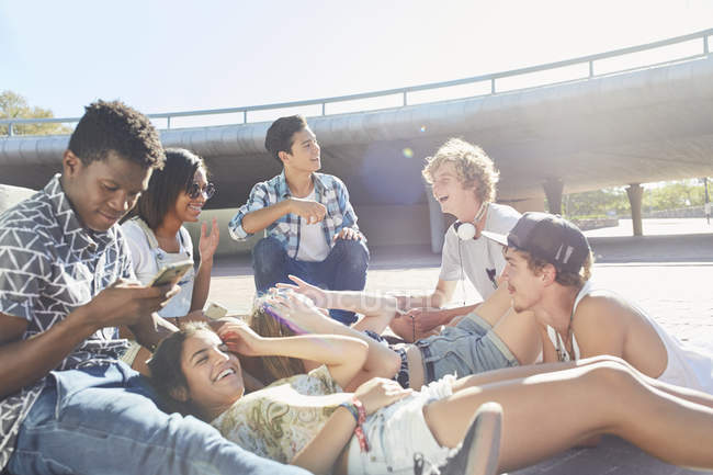 Teenage friends hanging out at sunny skate park — Stock Photo