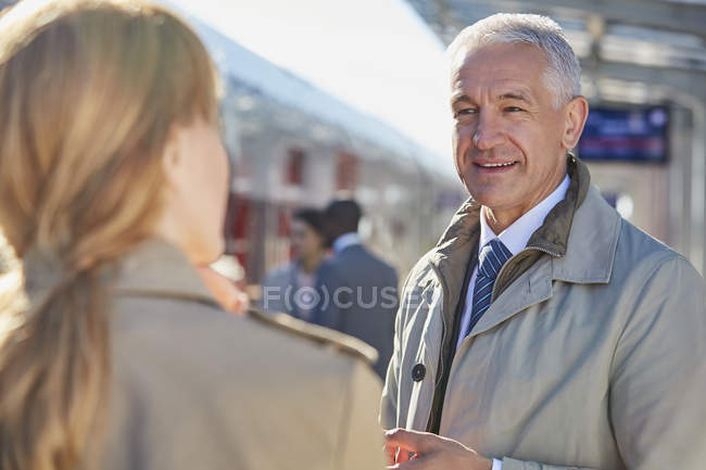 Businessman talking to businesswoman on train station platform — Stock Photo
