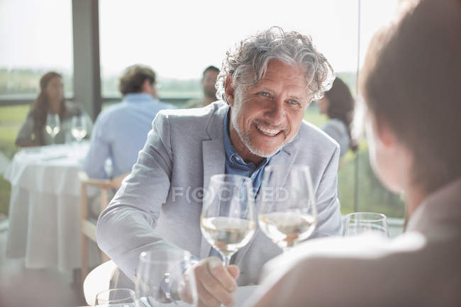 Pareja sonriente bebiendo vino en restaurante soleado - foto de stock