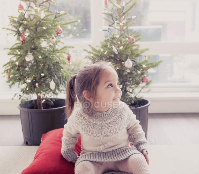 Ragazza sorridente di fronte ad alberi in vaso con luci di Natale — Foto stock