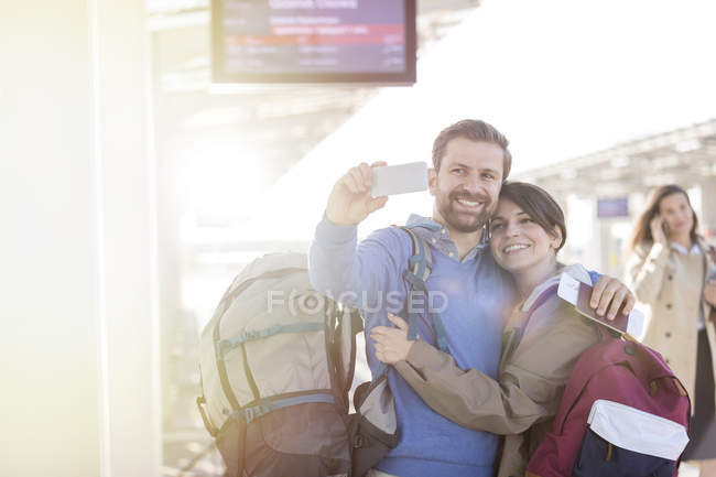 Casal com mochilas tirando selfie na estação de trem — Fotografia de Stock