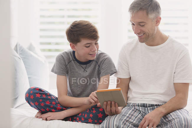 Отец и сын в пижаме с помощью цифрового планшета — стоковое фото