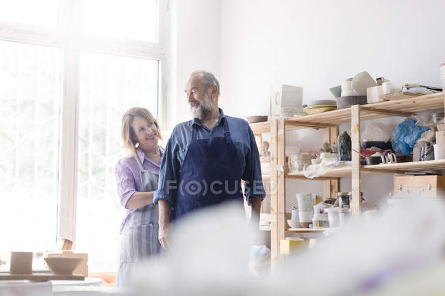 Wife tying husband?s apron in pottery studio — Stock Photo