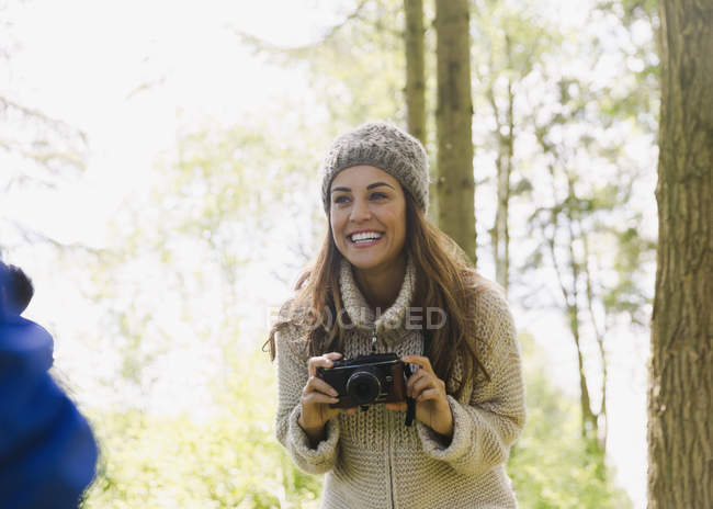 Усміхнена жінка використовує камеру в лісі — стокове фото