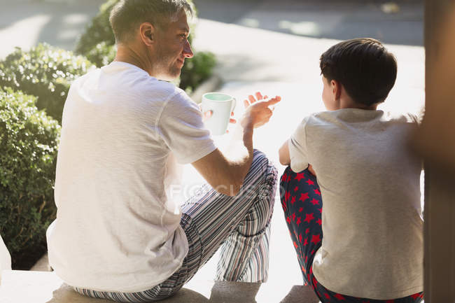 Père avec café parlant à son fils sur le perron avant — Photo de stock