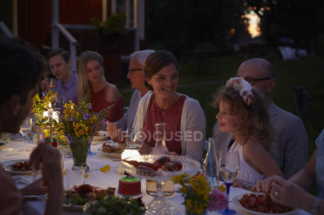 Familia disfrutando de la cena del patio a la luz de las velas por la noche - foto de stock