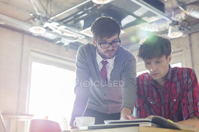 Creative businessmen reviewing document edits in sunny office — Stock Photo