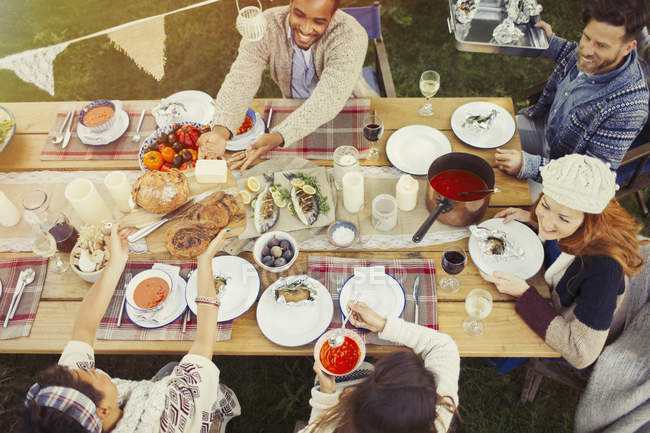 Друзья наслаждаются обедом за столом во дворе — стоковое фото