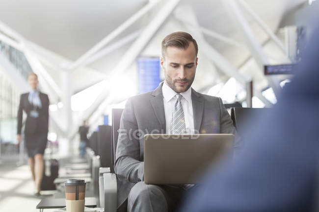 Businessman working using laptop in airport departure area — Stock Photo