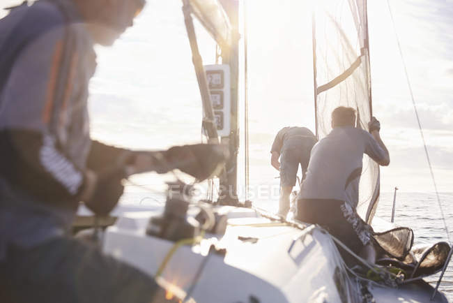 Men adjusting sailing equipment on sailboat — Stock Photo
