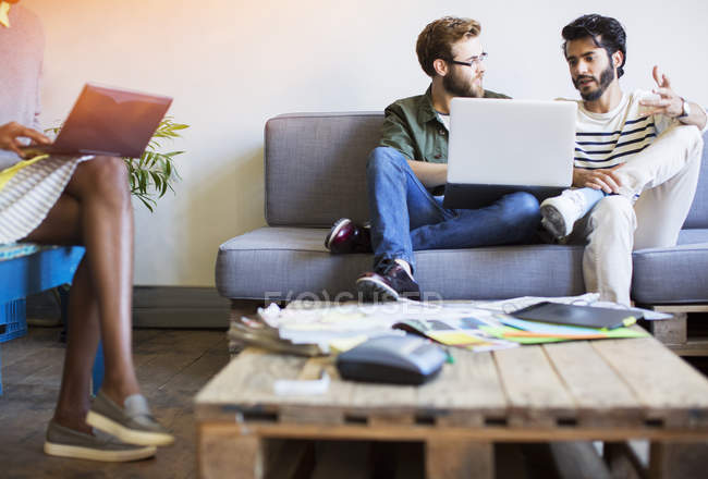 Случайные бизнесмены разговаривают и используют ноутбук на диване — стоковое фото