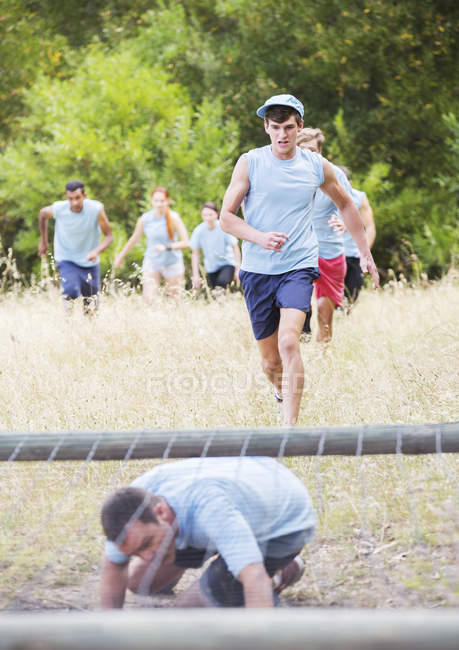Gente corriendo en el campo de entrenamiento carrera de obstáculos - foto de stock