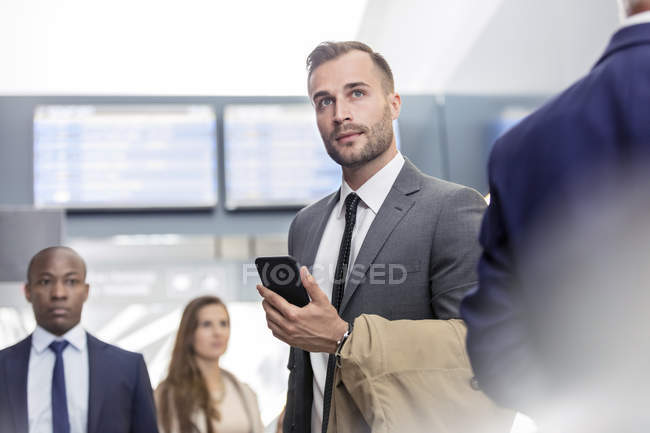 Homme d'affaires avec téléphone portable debout à l'aéroport — Photo de stock