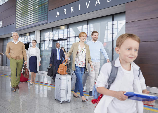 Viajeros con maletas caminando en el vestíbulo del aeropuerto - foto de stock