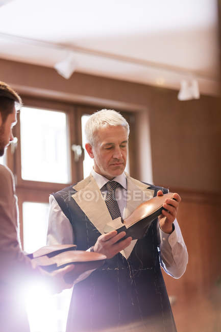 Businessman being fitted for suit examining dress shoes in menswear shop — Stock Photo