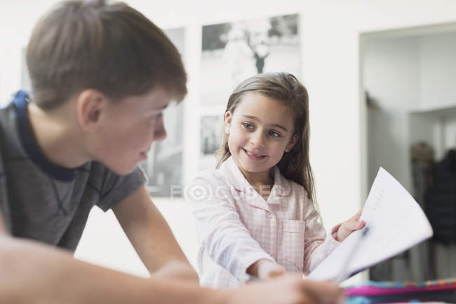 Orgogliosa sorella che mostra i compiti a casa al fratello — Foto stock