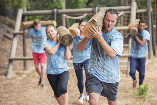 Entschlossene rennen mit Baumstämmen auf Bootcamp-Hindernisparcours — Stockfoto