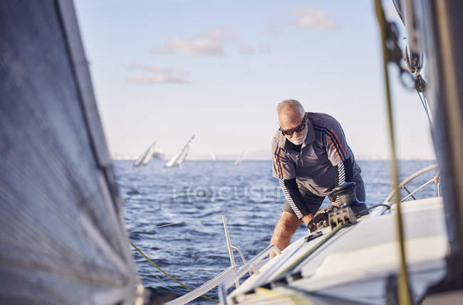 Caucasian senior retired man sailing sailboat — Stock Photo