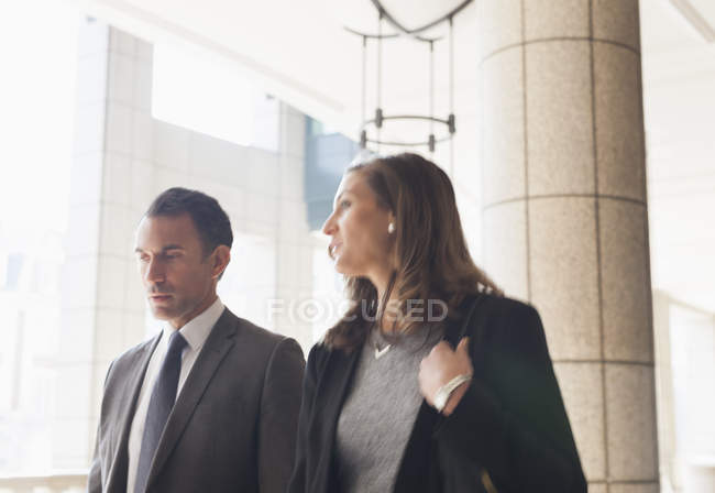 Corporate businessman and businesswoman talking and walking outdoors — Stock Photo