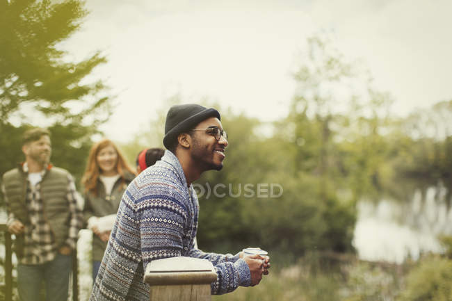 Smiling man drinking coffee at lakeside balcony — Stock Photo
