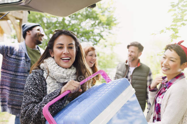 Portrait smiling woman with cooler at back of car with friends — Stock Photo