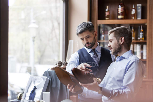Businessmen examining dress shoes in menswear shop — Stock Photo