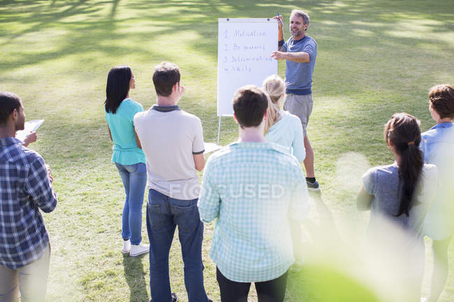Man leading meeting at flipchart in field — Stock Photo