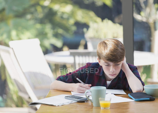 Мальчик делает уроки математики за обеденным столом — стоковое фото
