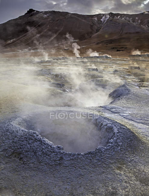 Дымящийся кратер на каменистой поверхности днем — стоковое фото