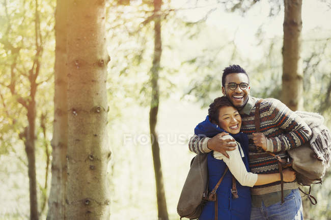 Casal brincalhão com mochilas abraçando caminhadas na floresta — Fotografia de Stock