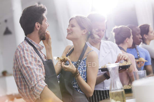 Wife feeding husband in cooking class kitchen — Stock Photo