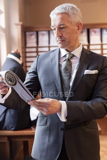 Бізнесмен переглядає тканину в магазині чоловічого одягу — стокове фото