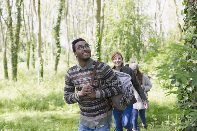 Amigos sonrientes caminando en el bosque durante el día - foto de stock