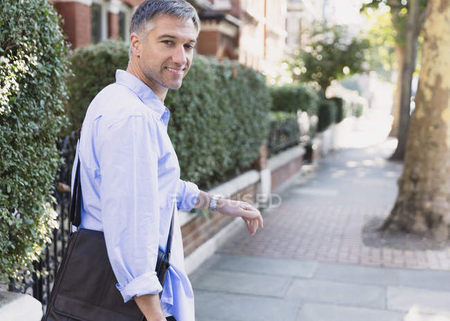 Portrait confident businessman walking and looking back on sidewalk — Stock Photo