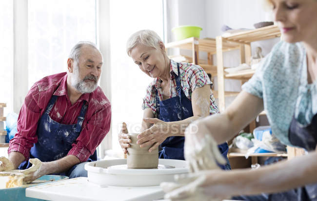 Senior couple using pottery wheel in studio — Stock Photo
