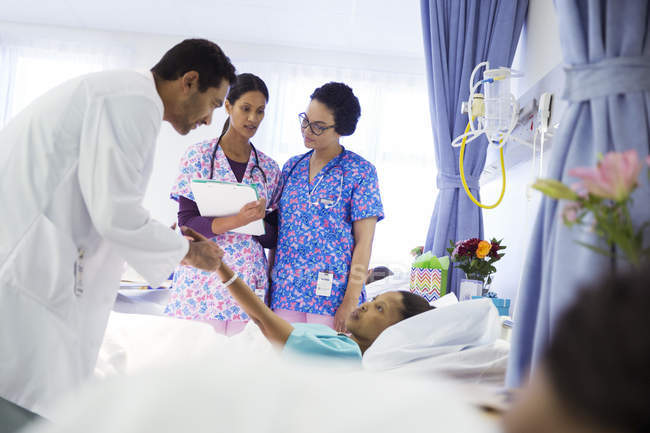 Médecin et infirmières faisant des rondes dans la chambre d'hôpital — Photo de stock