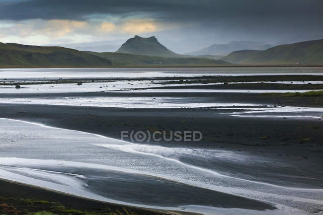 Acqua di mare ondulata contro riva e colline sullo sfondo — Foto stock