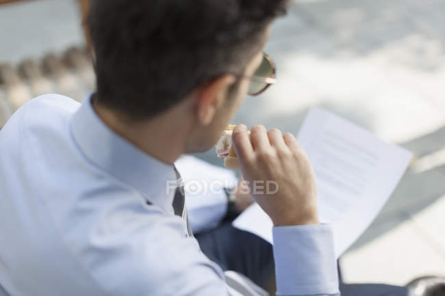 Geschäftsmann isst zu Mittag und liest Papiere — Stockfoto