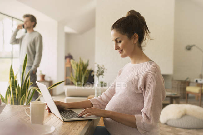 Schwangere benutzt Laptop am Esstisch — Stockfoto