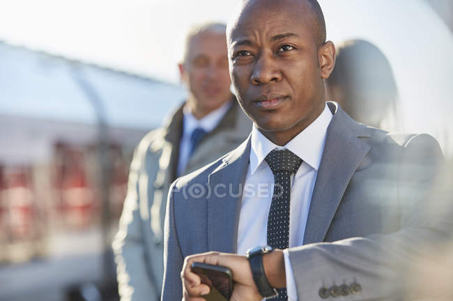 Businessman checking the time on wristwatch at train station — Stock Photo