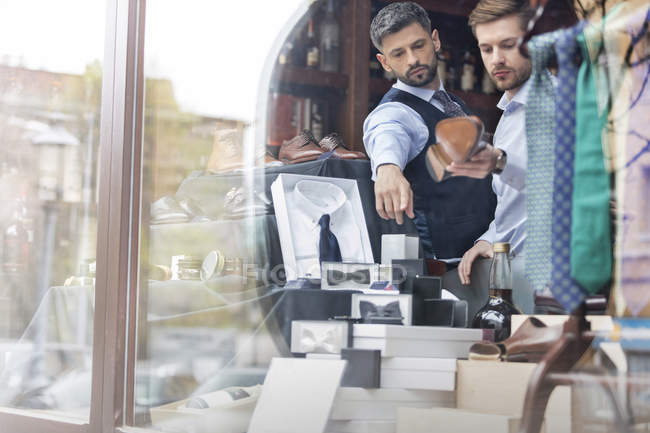 Рабочий, показывающий бизнесмену товар в витрине магазина мужской одежды — стоковое фото