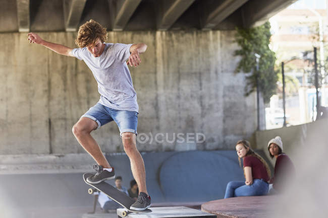 Adolescent garçon faire skateboard cascade à skate parc — Photo de stock
