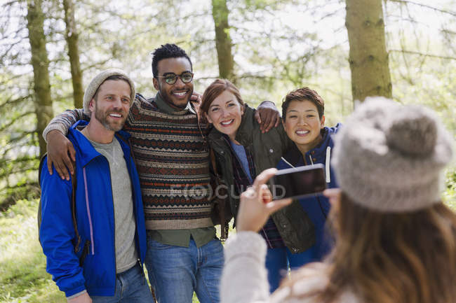 Mulher com câmera telefone fotografar amigos caminhadas na floresta — Fotografia de Stock