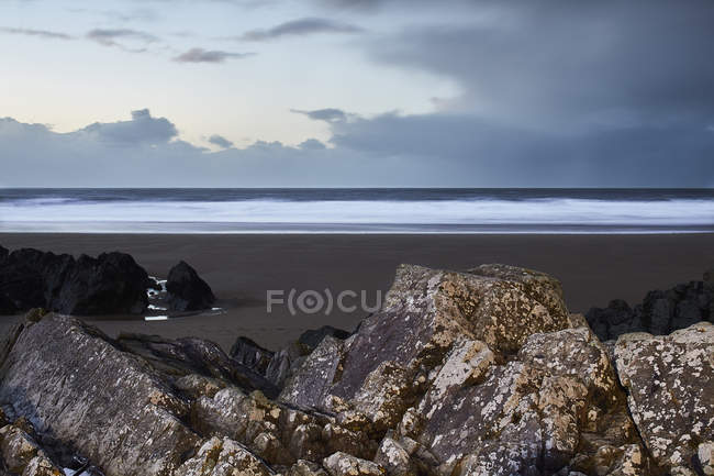 Seascape view behind rocks below overcast sky, Devon, United Kingdom — Stock Photo