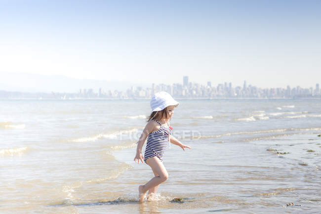 Girl wading in surf on beach — Stock Photo