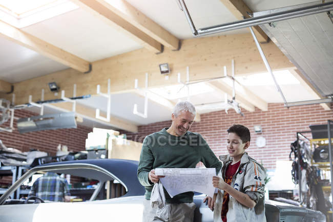 Father and son reviewing plans in auto repair shop — Stock Photo