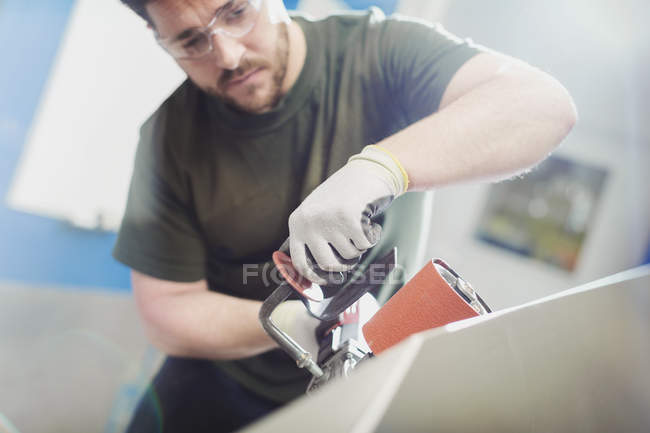 Worker using sander in steel factory — Stock Photo