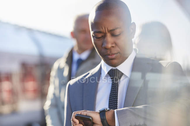 Uomo d'affari che controlla l'ora sull'orologio da polso alla stazione ferroviaria — Foto stock