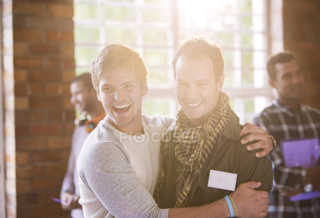 Усміхнені молоді чоловіки обіймаються на семінарі — стокове фото